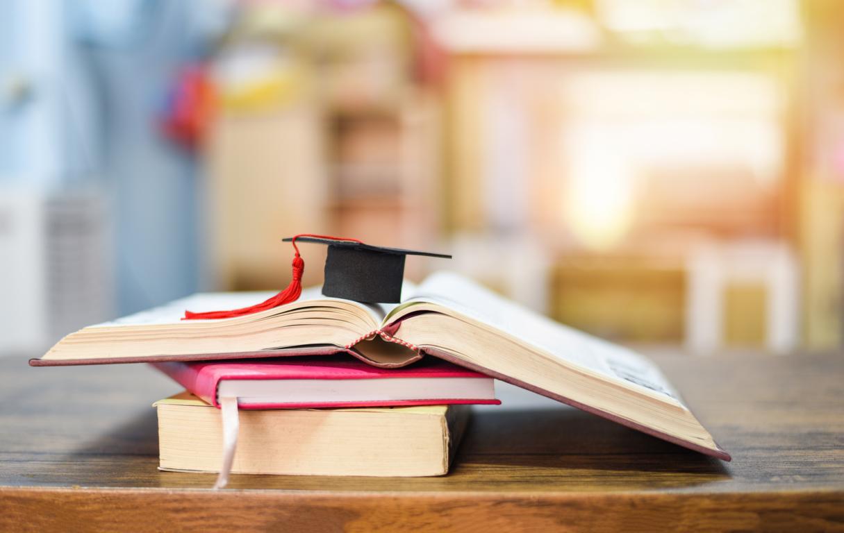 Education concept with graduation cap on a book on the wooden ta