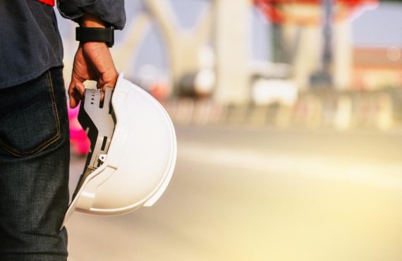 Close up engineer hold hard hat site construction background
