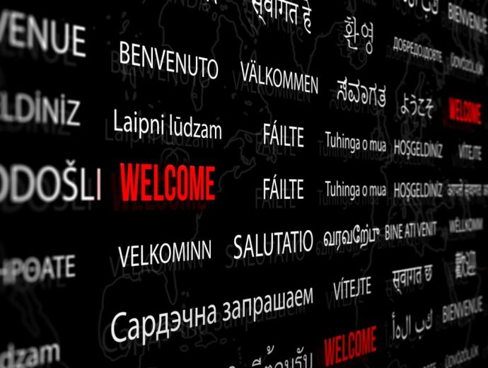 Welcome in different language with world map background. Depth of field image. Words cloud concept.