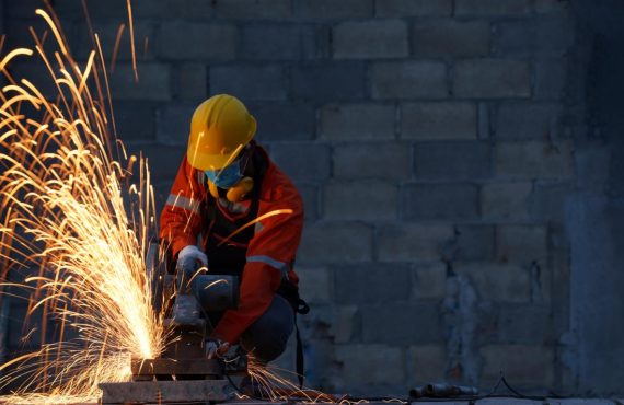 Worker wearing protective mask to Protect Against Covid-19,Sparks from sawing metal at a construction site,Worker using grinder steel and have throwing sparks.